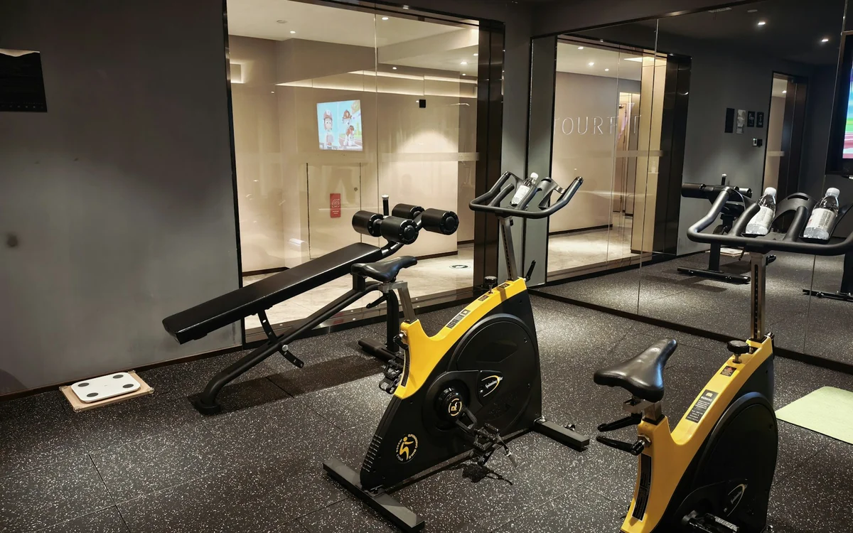 Modern home gym with exercise bikes, strength equipment, mirrors, and resilient flooring