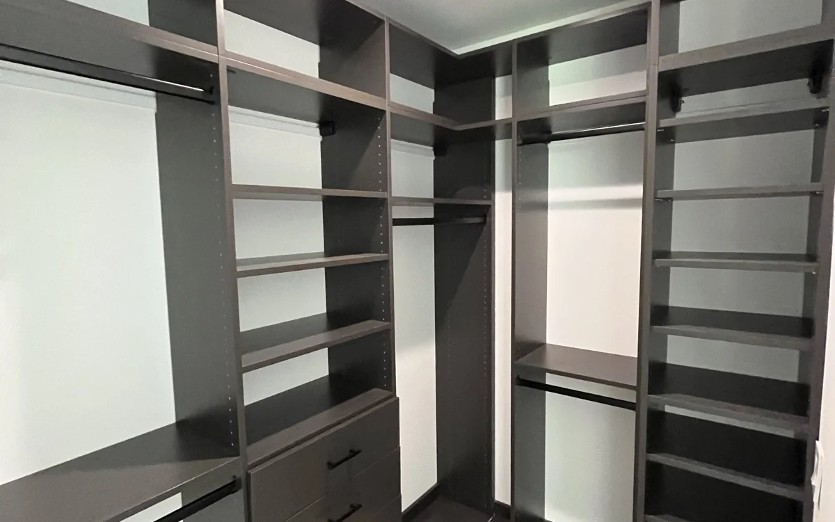 Custom dark wood walk-in closet built-ins with shelves, drawers, and hanging storage