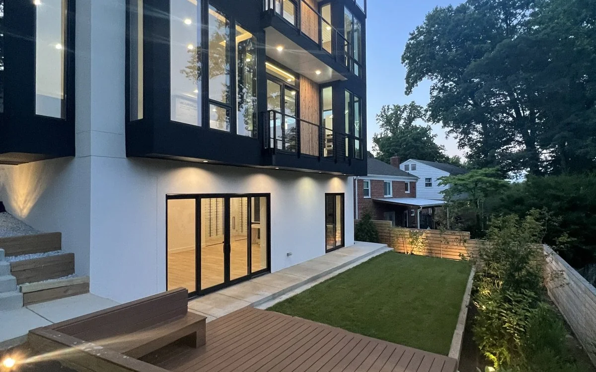 Modern home exterior renovation with new siding, large windows, lighting, and landscaped outdoor space