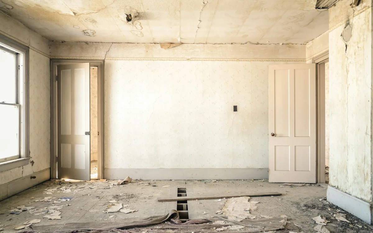 Damaged interior room with deteriorated walls and flooring awaiting professional restoration