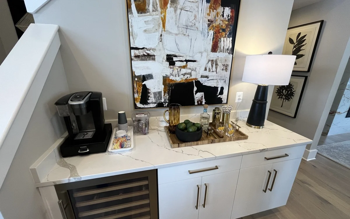 Built-in home wet bar with beverage refrigerator, quartz counter, cabinets, and serving area