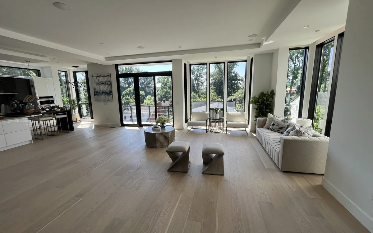 Open-concept renovated living room with modern windows, light wood floors, and flexible seating