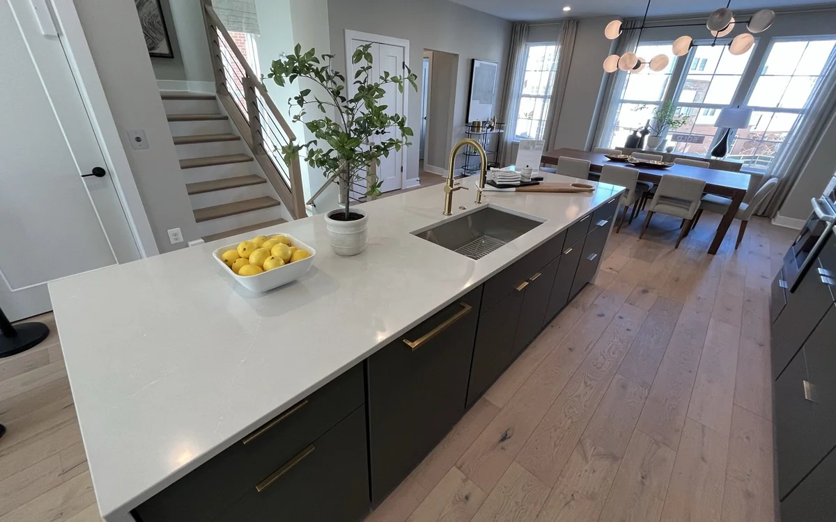 Updated kitchen with a large quartz island, modern cabinetry, and refinished wood floors