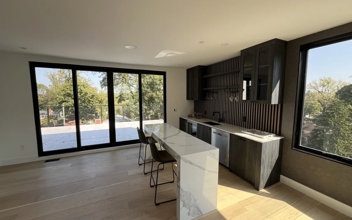 Compact modern kitchen suited to an in-law suite with dark cabinetry and large windows