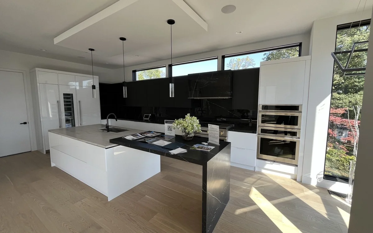Open modern kitchen showing continuous wide-plank flooring through a high-traffic living area