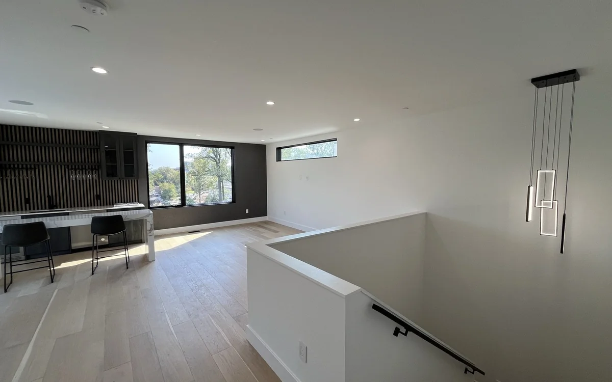 Open-concept upper level connecting kitchen, living space, staircase, and abundant natural light