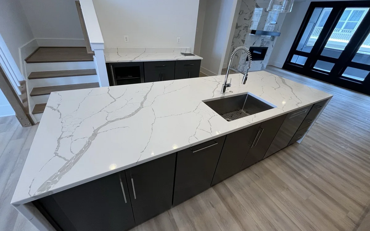 Waterfall-edge stone kitchen island showing veining, polished finish, and integrated cabinetry