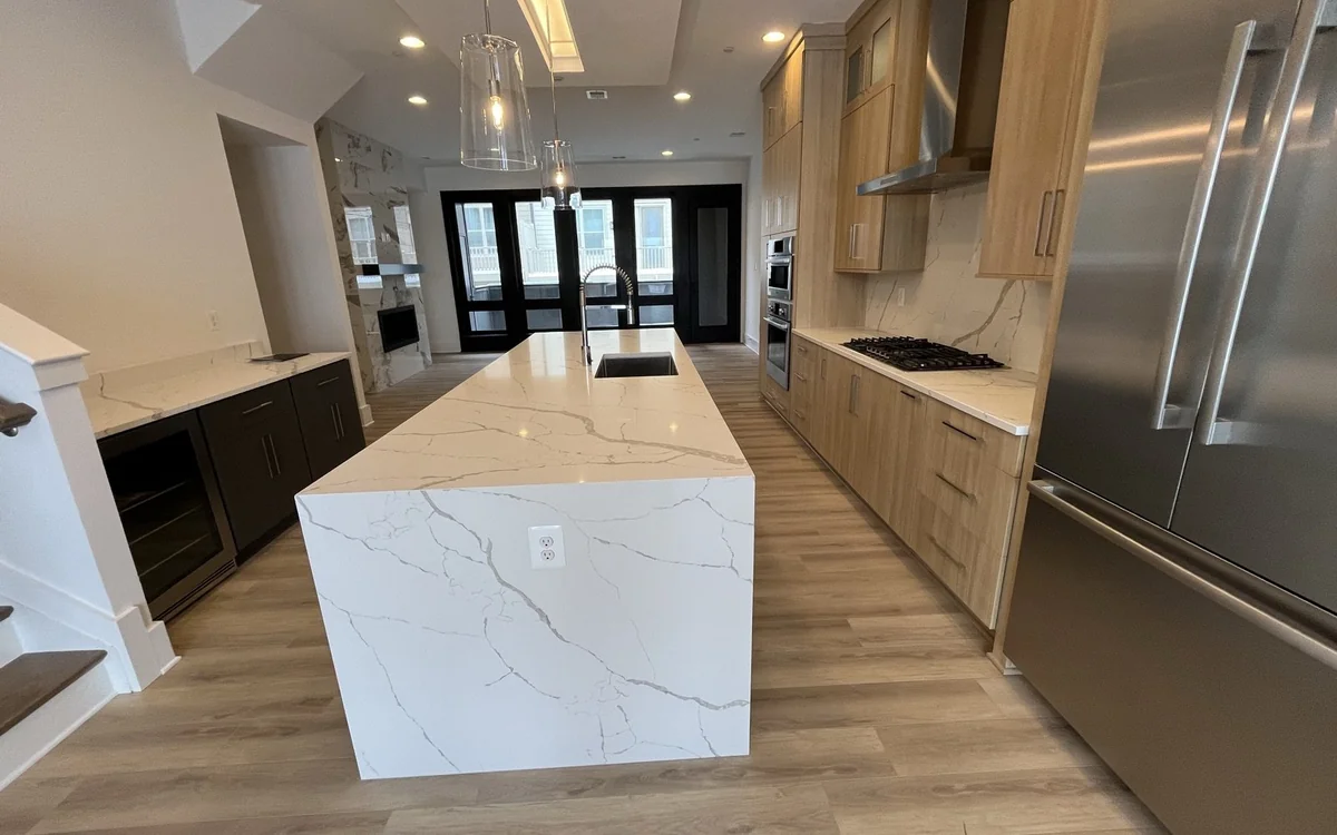 Full kitchen renovation with custom cabinetry, large stone island, appliances, and hardwood flooring