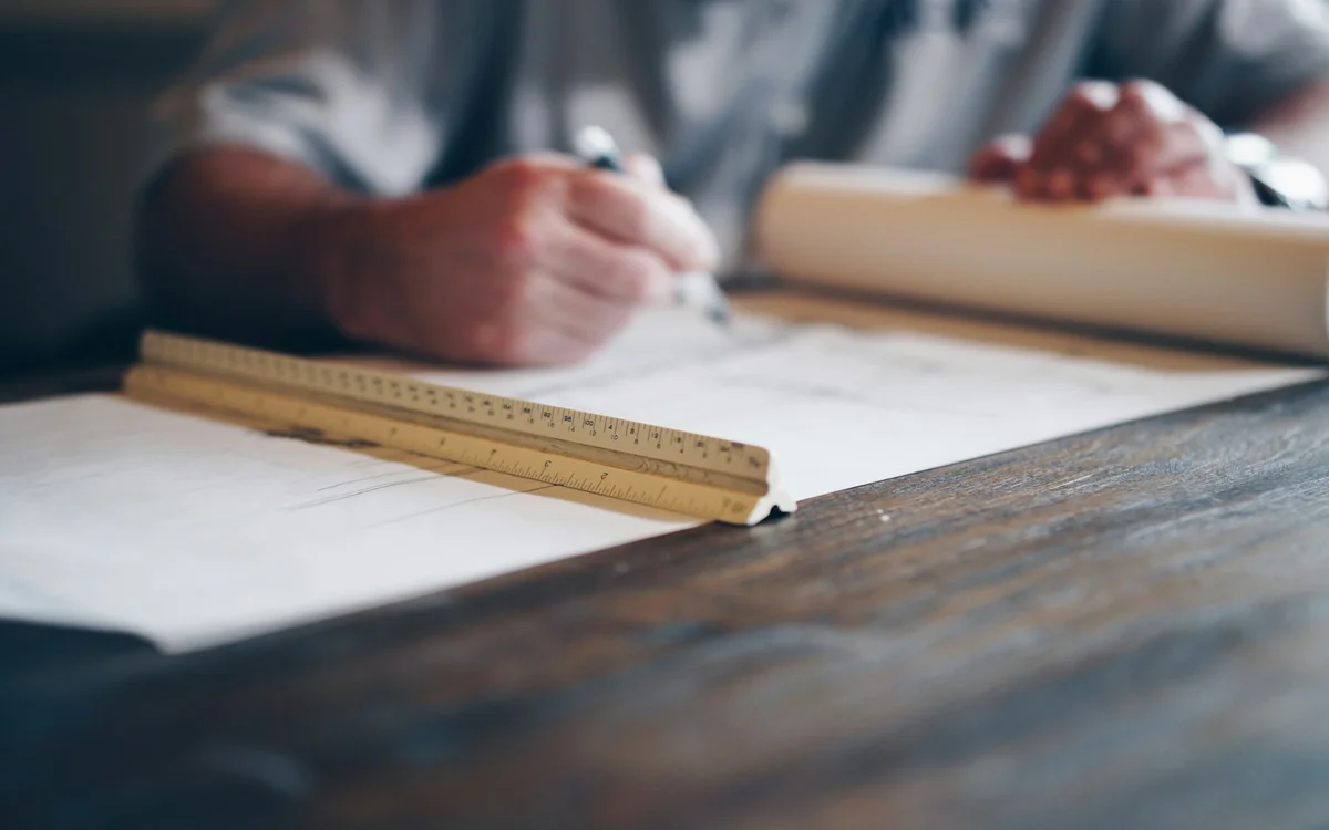 Designer drafting construction plans with a ruler as part of an integrated design-build process
